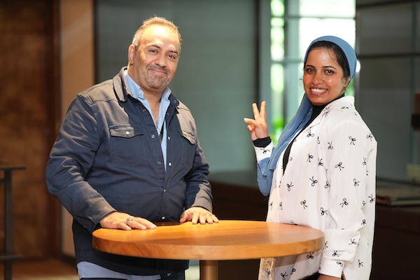 A man and woman stand side by side, smiling for a picture