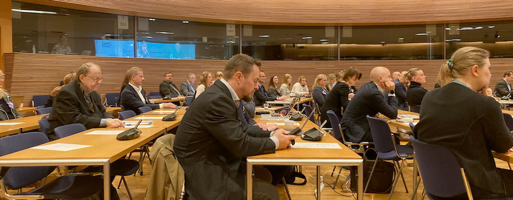 People in business-style clothing sit at rows of tables