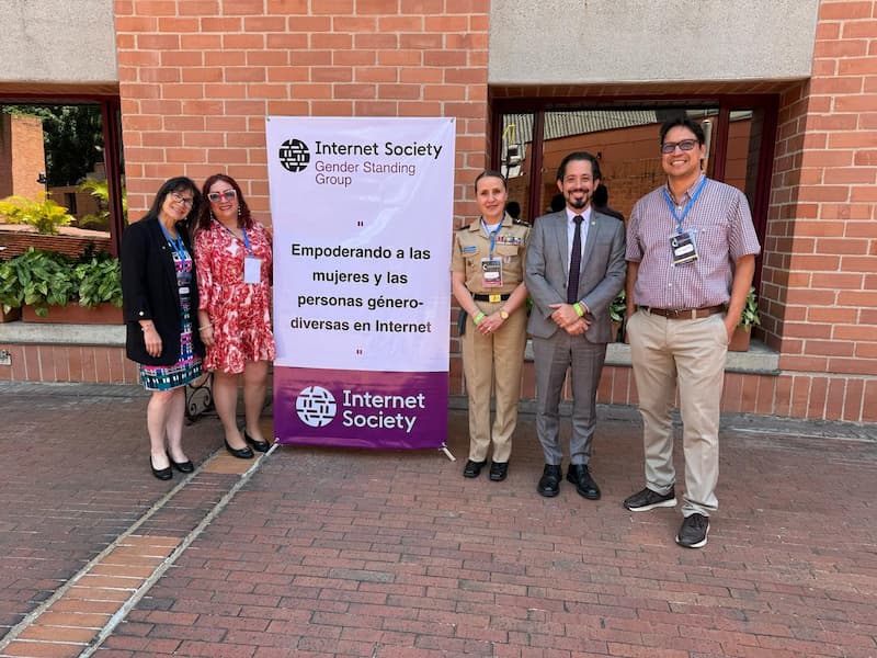 three women and two men posing for a photo next to the banner 
