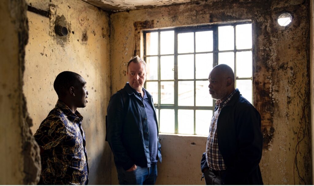 Three men stand inside of the burnt Tanda Net