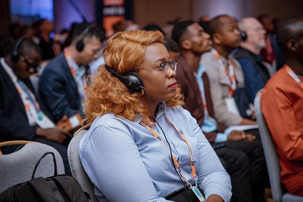 A woman sits and wears headphones
